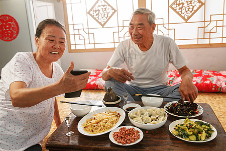 老年夫妇在家里吃饭看手机高清图片
