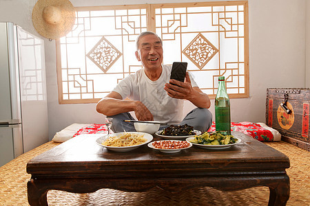 老年人坐在家里吃饭看手机图片