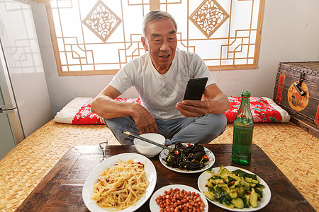 中国白酒老年人坐在家里吃饭看手机背景