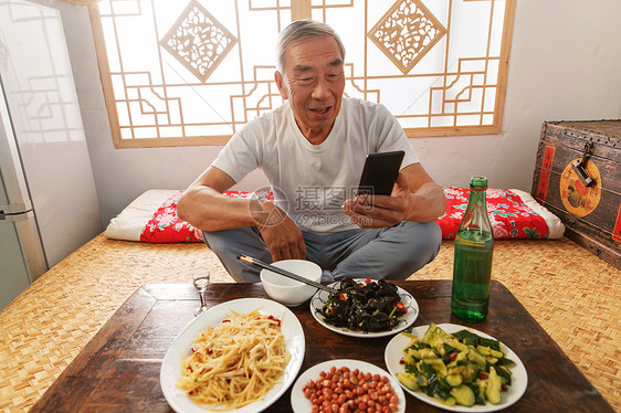 老年人坐在家里吃饭看手机图片