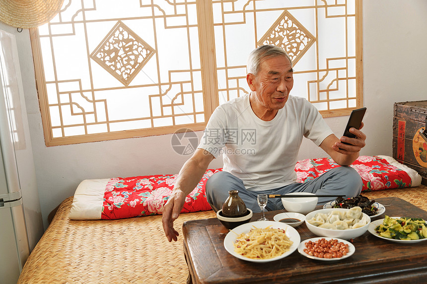 老年人坐在家里吃饭看手机图片