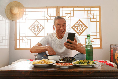 老年人坐在家里吃饭看手机图片
