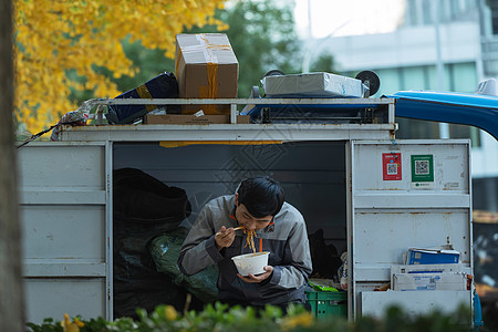 快递员坐在快递车上吃面高清图片