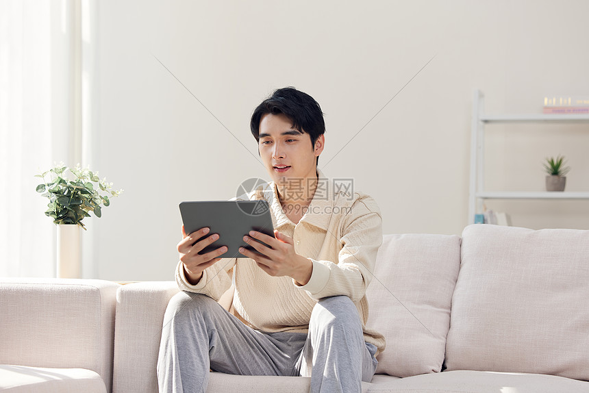 沙发上使用平板电脑的男性图片