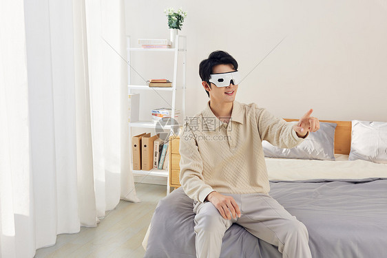 男性坐在床上操作vr虚拟屏幕图片