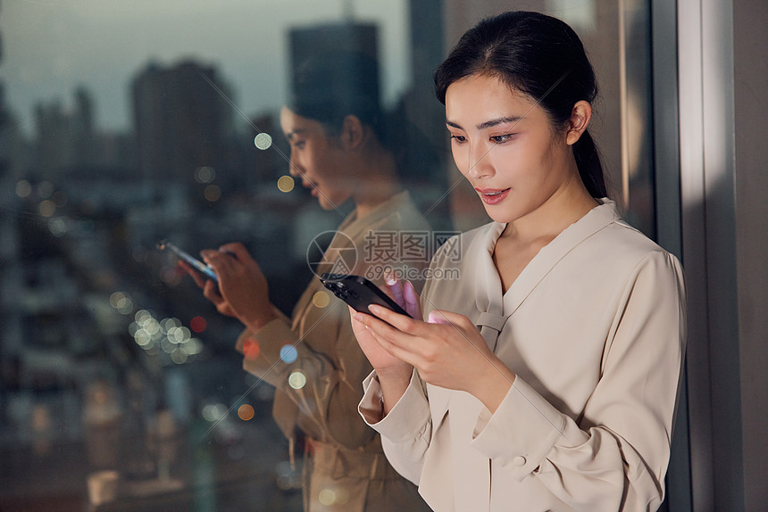 职业女性在窗边看手机图片