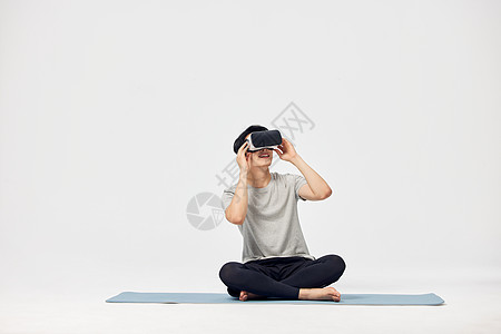 VR虚拟世界男性坐在瑜伽垫上体验vr设备背景