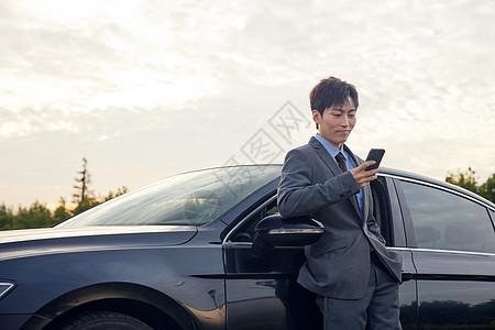 站在车边休息看手机的商务男性图片