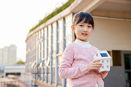 风车儿童手拿太阳能面板房屋模型的小女孩背景