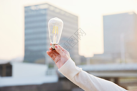 户外手拿节能电灯泡特写图片