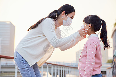 户外妈妈帮女儿戴口罩图片