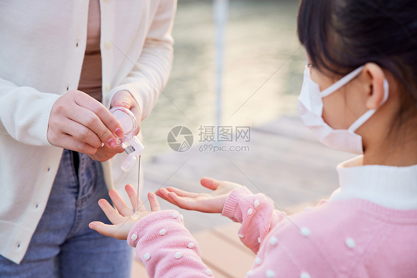户外母女使用凝胶护手消毒特写图片