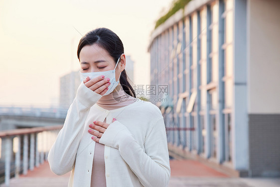 室外咳嗽戴口罩的青年女性图片