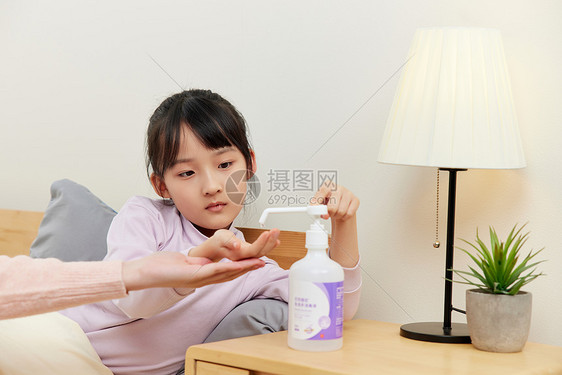 生病卧床的小女孩使用消毒凝胶图片