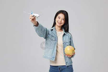 年轻女性手拿地球仪和飞机模型图片