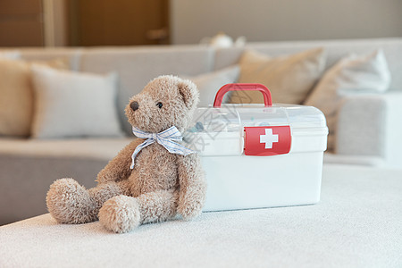 坐在沙发上熊家用医疗箱和小熊玩偶背景