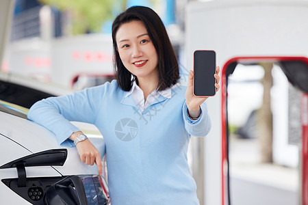 手机充电桩女性靠在新能源汽车旁展示手机屏幕背景