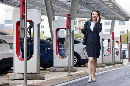 新能源汽车充电桩旁打电话的商务女性图片