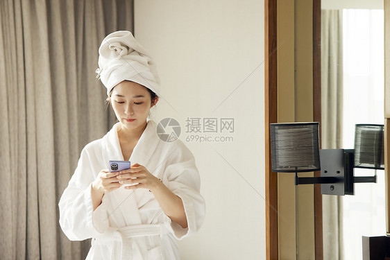 年轻美女酒店度假休闲玩手机图片
