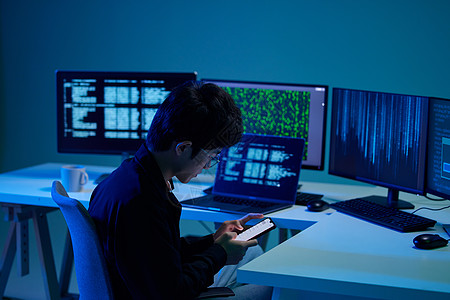 台式电脑年轻男程序员工作间隙玩手机背景