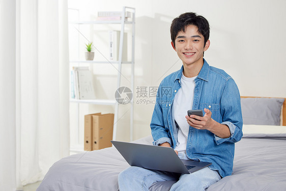 年轻男性使用笔记本电脑和手机图片