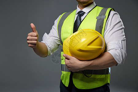 建筑工人抱着安全帽点赞特写图片