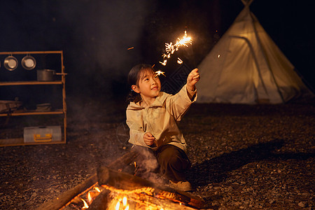 小女孩夜晚露营篝火放烟花高清图片