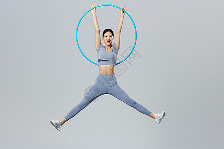 创意健身女性手举起呼啦圈跳跃图片