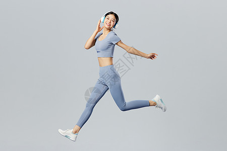 创意跳跃健身女性戴耳机听歌健身背景图片