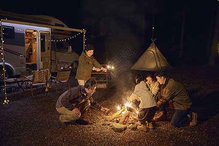 夜晚户外房车露营篝火的大家庭图片