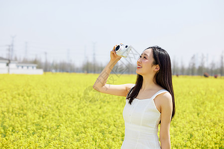 使用相机拍摄油菜花海的女性图片