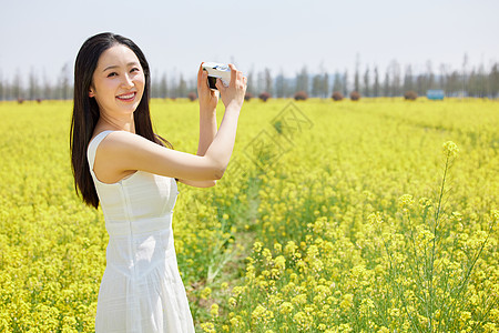 相机拍摄油菜花海的美女图片