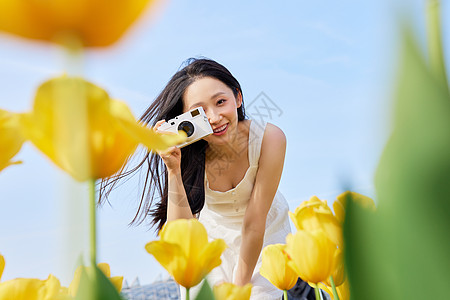春天与少女背景郁金香前景手拿照相机的美女背景