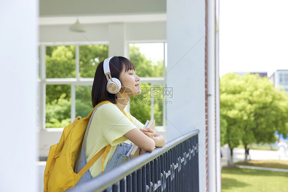 校园里听音乐的女大学生形象图片