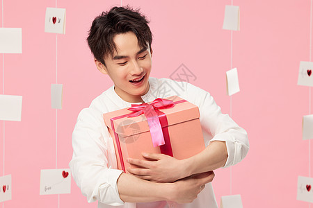 粉色背景抱着礼物的男生图片