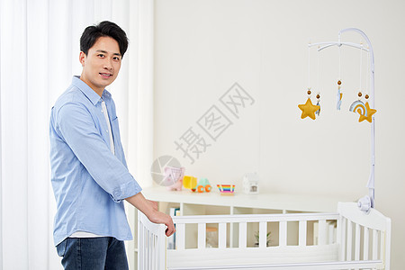 年轻奶爸布置婴儿房背景图片