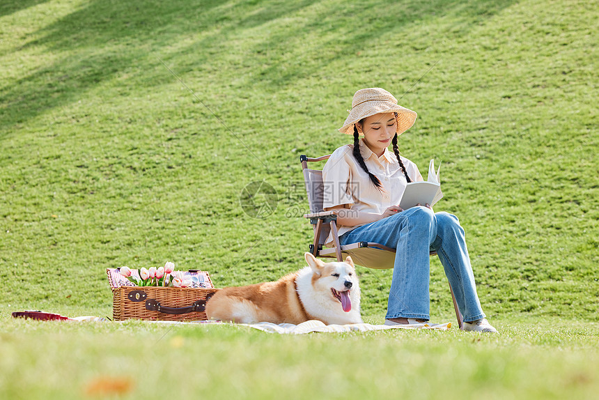 公园里休闲看书的女主人和宠物狗图片