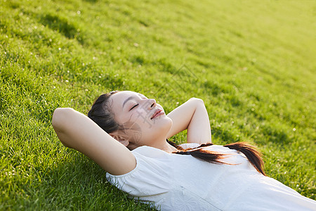 文艺少女躺在草地上闭眼晒太阳的白裙少女背景