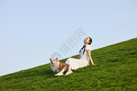柯基和主人坐在草地上享受阳光图片