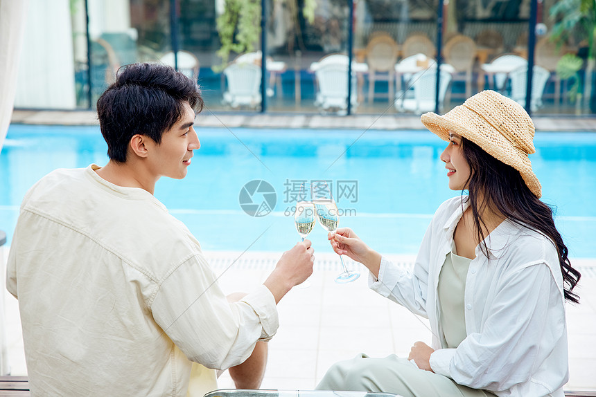 年轻情侣度假泳池边喝香槟图片