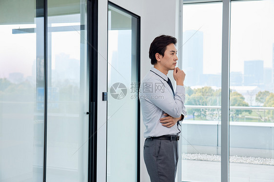 站在窗前放松休息的商务男士图片