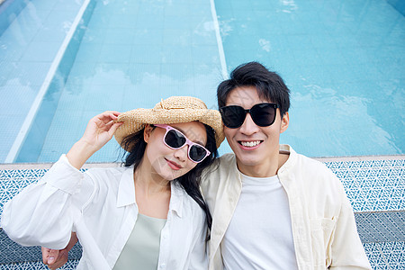 夫妻旅游泳池边戴太阳镜的年轻情侣背景