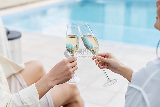 泳池边情侣喝香槟特写图片