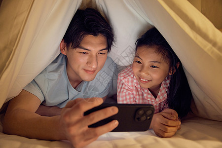 父亲和女儿藏在被窝里看手机高清图片