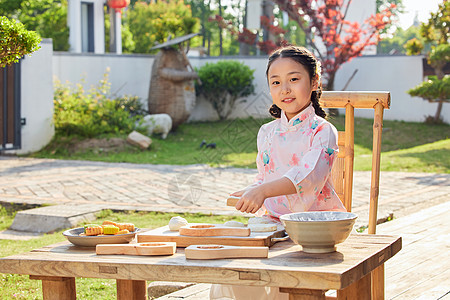 室外穿着汉服的小女孩制作月饼图片