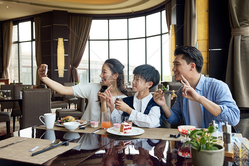 一家人在自助餐厅使用手机合照图片