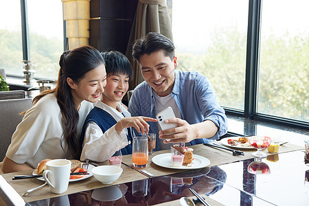餐厅桌上看手机的一家人图片