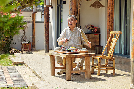 老人坐在院子里悠闲喝茶图片