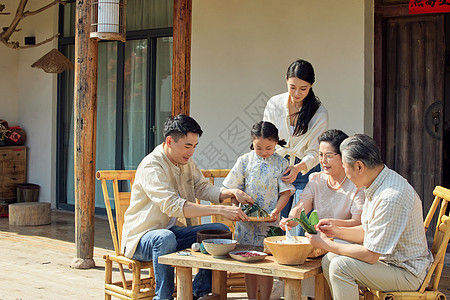 祖孙三代端午节在院子里包粽子的一家五口背景