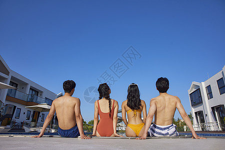 泳装年轻人们坐在泳池边背影图片
